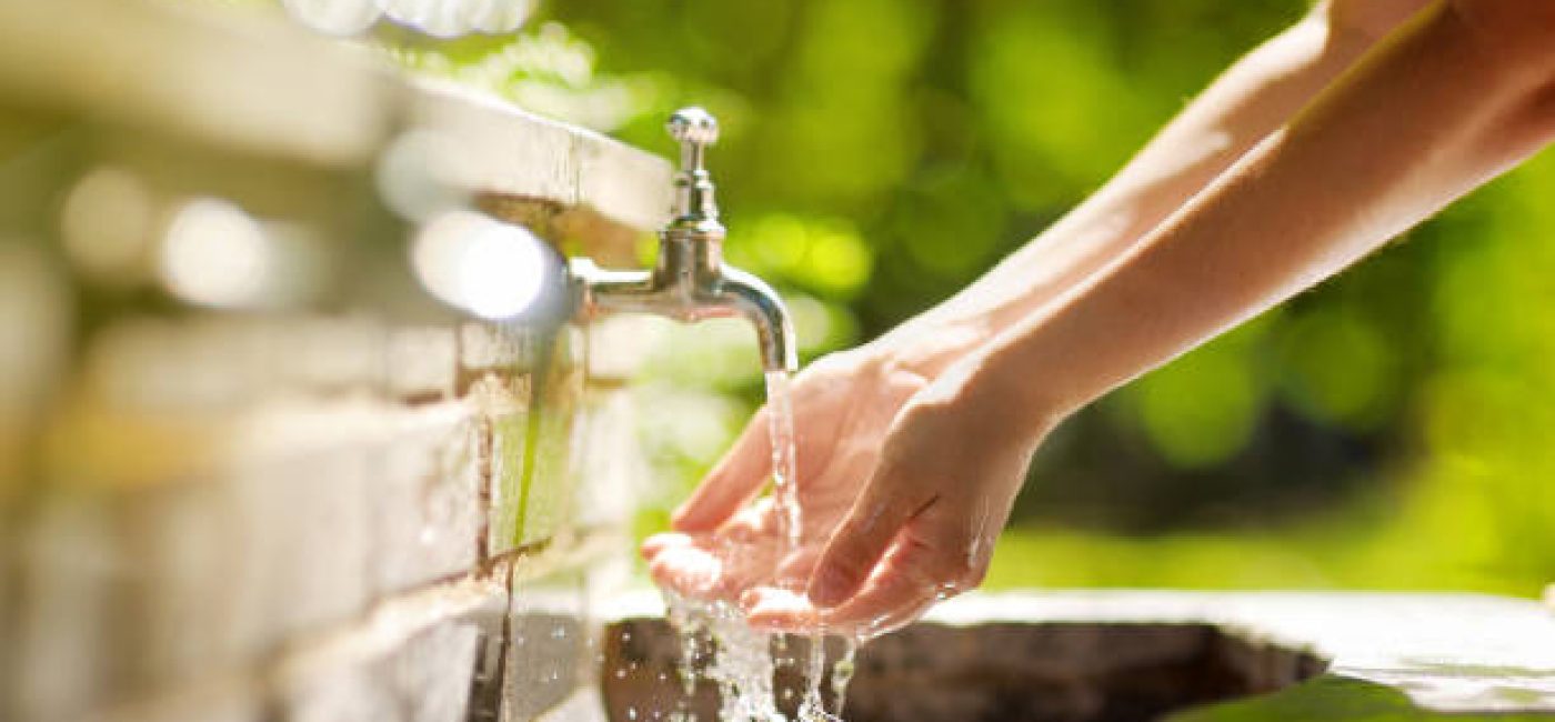 Closeup photo of woman washing hands in a city fountain. Young woman drinking clean water from the fountain in Rome, Italy